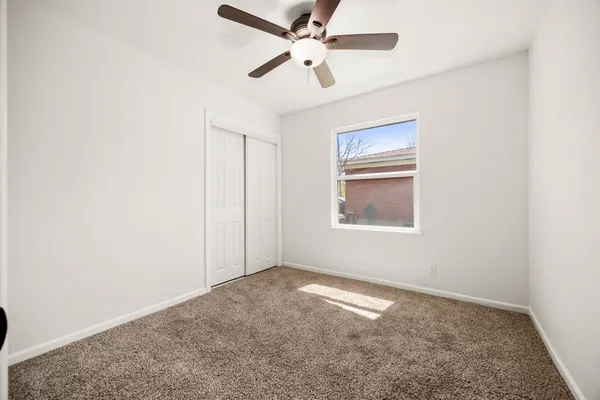 an empty room with windows and fan