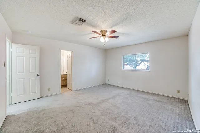 an empty room with windows and fan