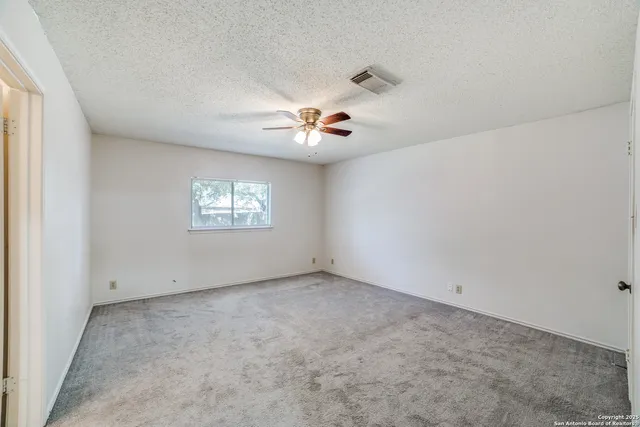 an empty room with a window and a ceiling fan
