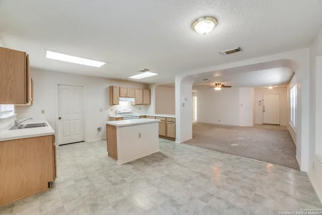 a view of a kitchen with a sink and dishwasher a refrigerator with white cabinets