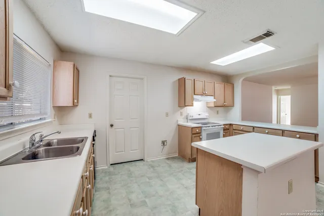 a kitchen with a sink stove top oven and refrigerator
