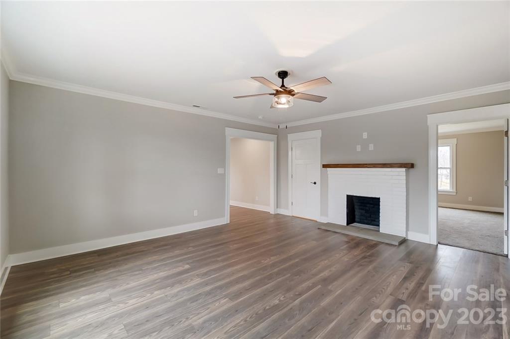 3711 Sikes Mill Road Monroe, NC 28110 - Photo 17 of 46 a view of an empty room with wooden floor and a fireplace