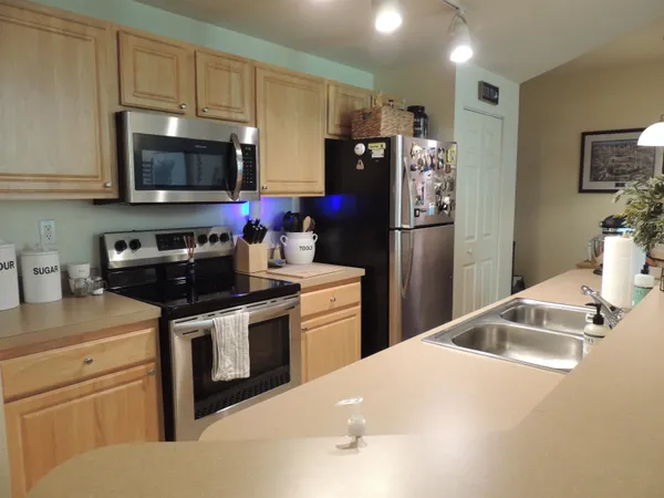 a kitchen with stainless steel appliances a stove a sink a refrigerator a microwave oven and cabinets
