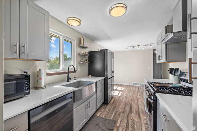 564 Swenson Avenue Springville, UT 84663 - Photo 5 of 26 Kitchen featuring wood-finish flooring, light grey cabinetry, white countertops, a stainless steel farmhouse sink, and a stainless steel gas range with a matching hood