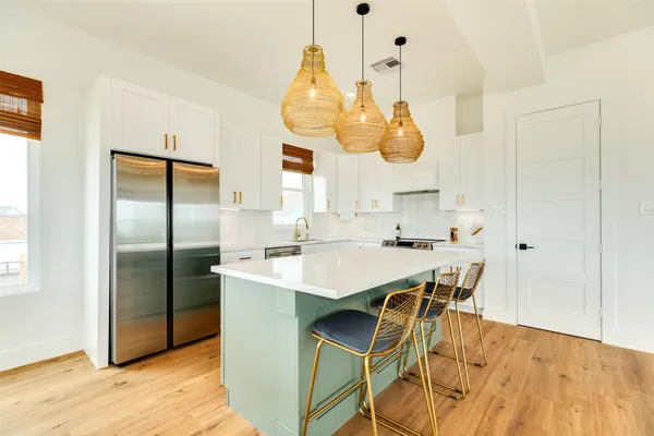 a kitchen with stainless steel appliances granite countertop a sink a microwave refrigerator and chairs