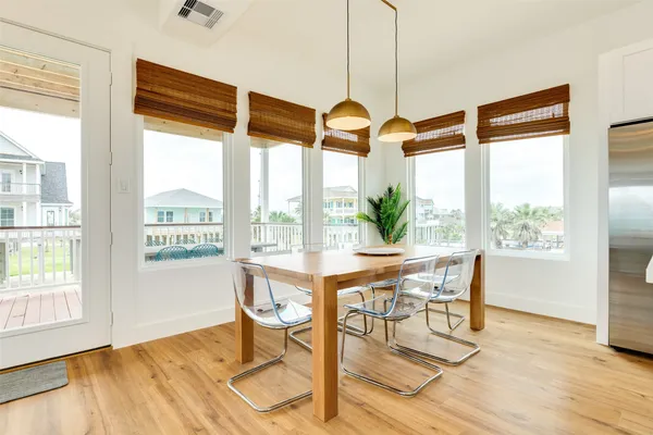a dining room with wooden floor and large windows