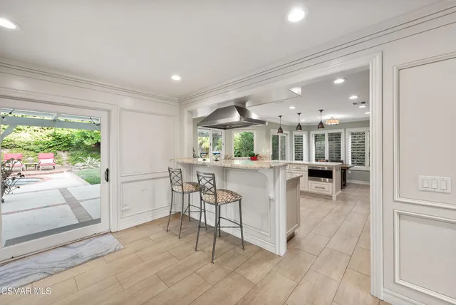 a dining hall with stainless steel appliances a dining table wooden floor and a large window