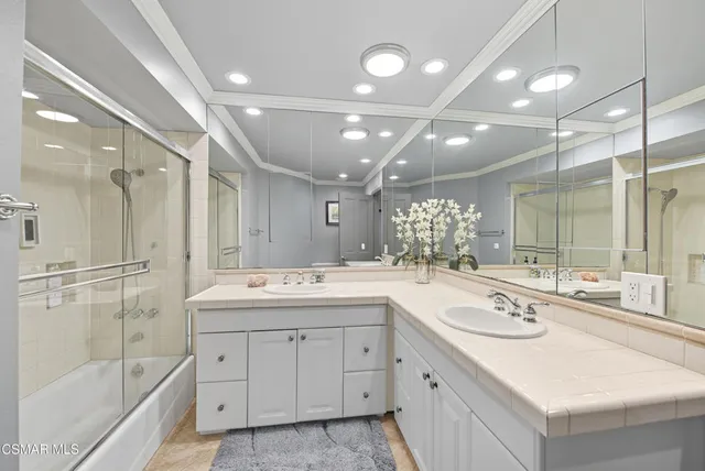 a bathroom with a sink double vanity granite tub shower and a mirror