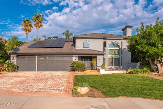 a front view of a house with a yard and trees