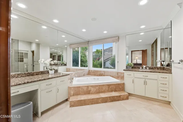 a large white kitchen with granite countertop a large window and white cabinets