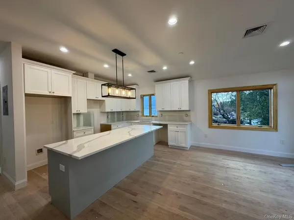 a large kitchen with stainless steel appliances kitchen island a large counter top and wooden floors