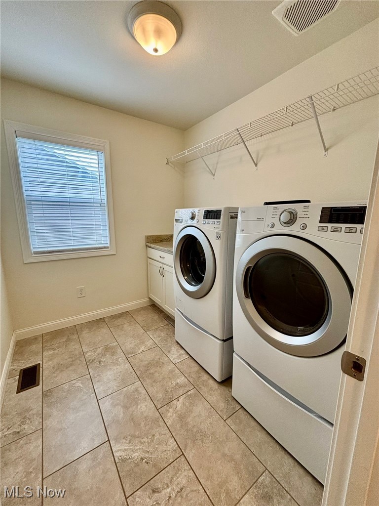 1132 Hummingbird Way Findlay, OH 45840 - Photo 19 of 28 Laundry room featuring washing machine and clothes dryer, cabinet space, and light tile patterned flooring