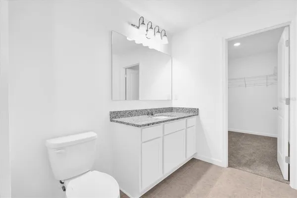 a bathroom with a granite countertop toilet and a sink