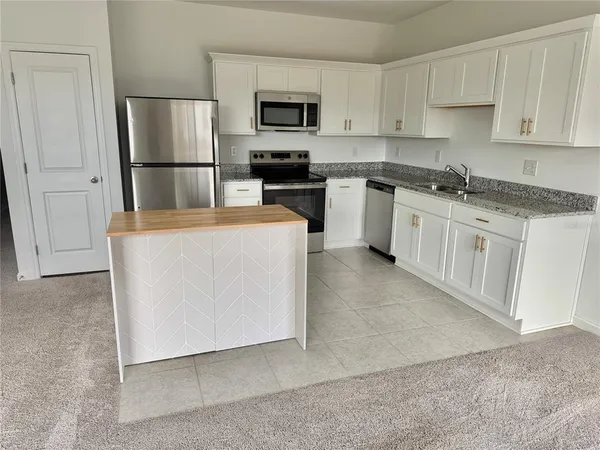 a kitchen with stainless steel appliances granite countertop a refrigerator stove a sink and a microwave