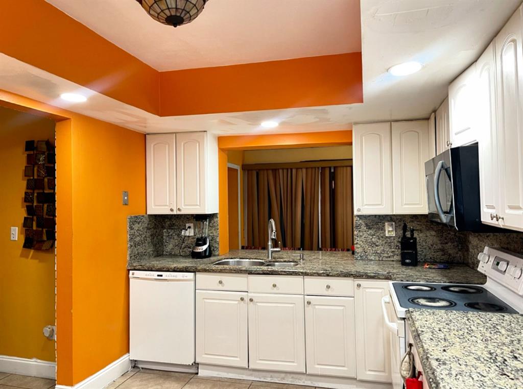 a kitchen with granite countertop a sink a stove and cabinets