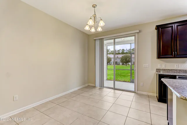 a view of an empty room with window and kitchen view