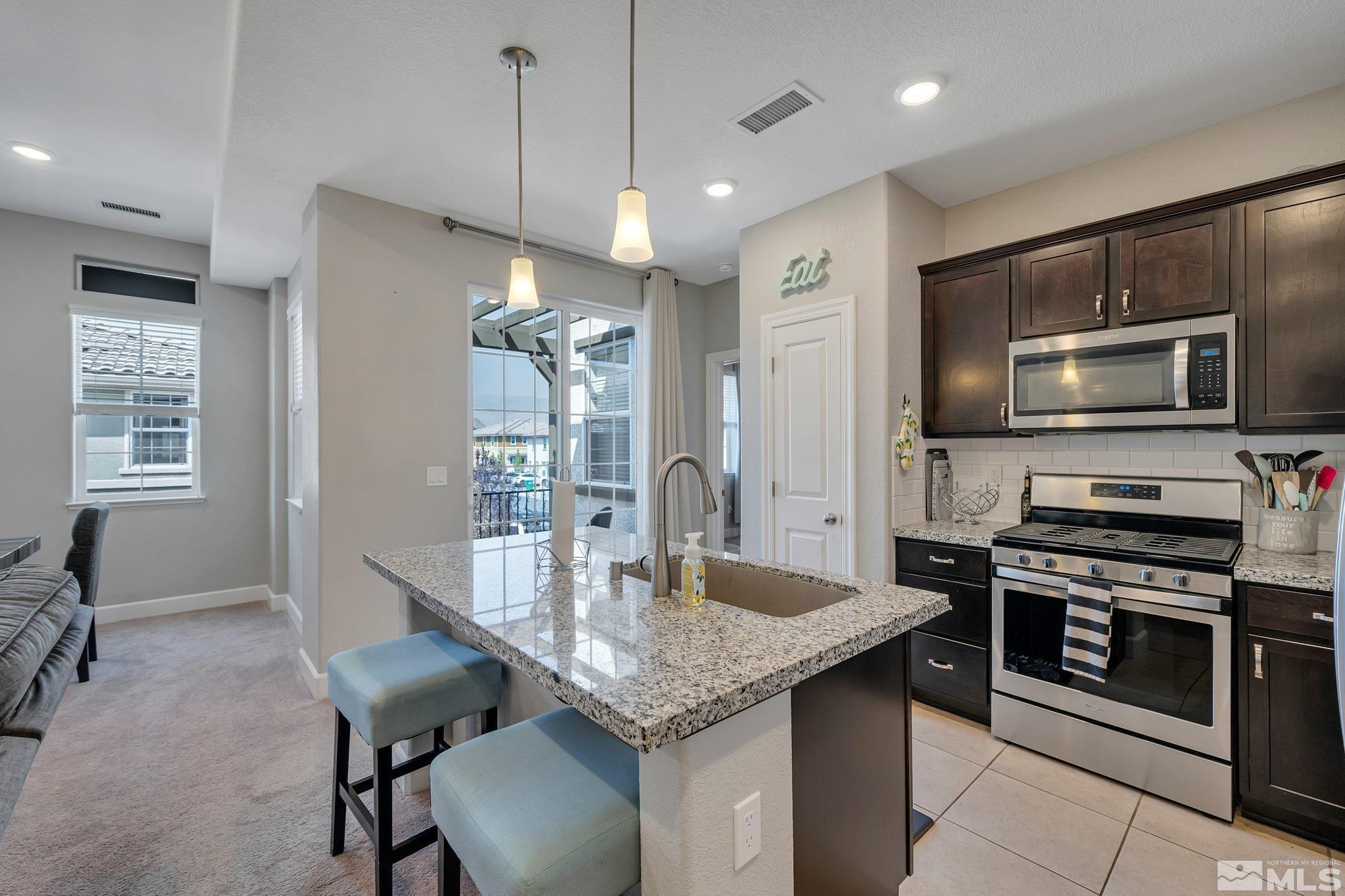 1914 Sea Horse Road, Unit A Reno, NV 89521 - Photo 5 of 28 a kitchen with stainless steel appliances granite countertop a stove top oven a sink dishwasher a dining table and chairs