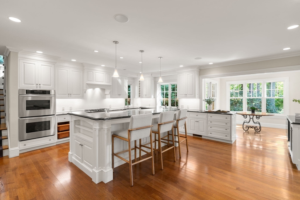 182 Winding River Road Wellesley, MA 02482 - Photo 4 of 40 a kitchen with stainless steel appliances granite countertop a stove top oven a sink dishwasher a dining table and chairs with wooden floor