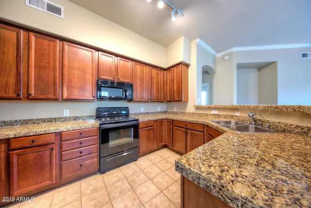 a kitchen with stainless steel appliances granite countertop wooden cabinets a stove top oven a sink and dishwasher
