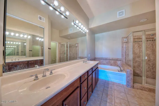 a bathroom with a sink double vanity granite tub shower and a mirror
