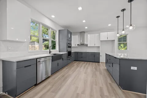 a large kitchen with a large counter top a sink stainless steel appliances and cabinets