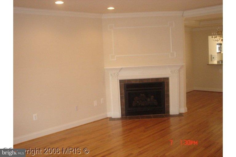 a view of an empty room with wooden floor and a fireplace
