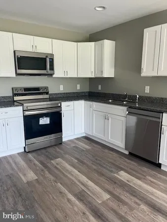 a kitchen with granite countertop a stove a sink and a microwave