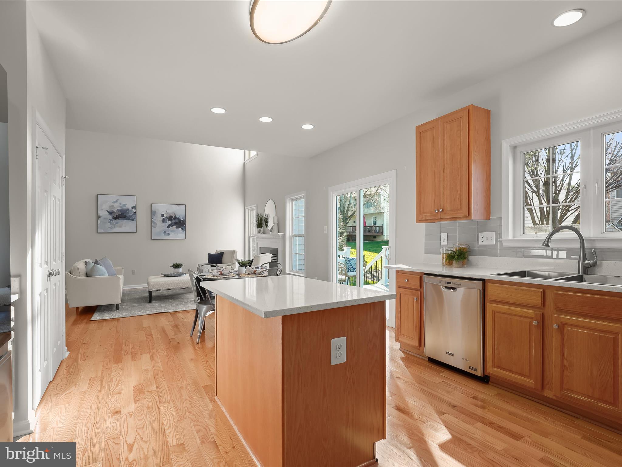 6413 Phantom Moon Walk Clarksville, MD 21029 - Photo 60 of 60 a large kitchen with kitchen island a sink dishwasher a dining table and chairs with wooden floor