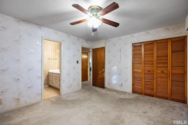 an empty room with closet and a chandelier fan
