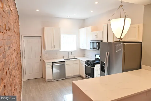 a kitchen with stainless steel appliances a refrigerator sink and wooden floor