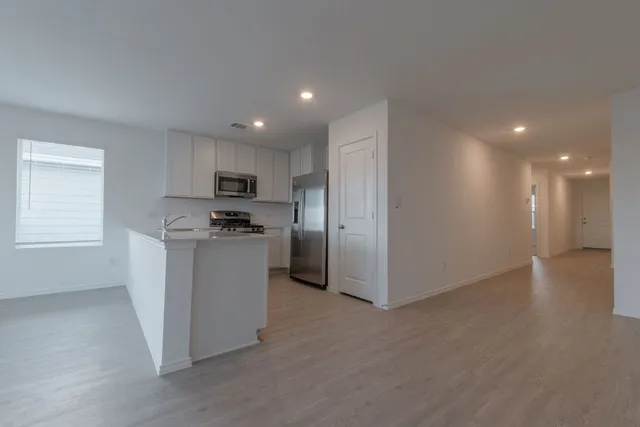 a view of an empty room with a window and wooden floor