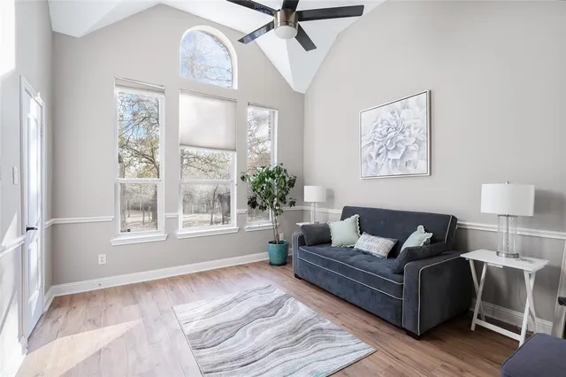 a living room with furniture large window and wooden floor