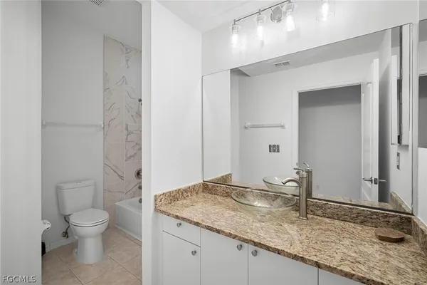 a bathroom with a granite countertop sink a toilet and a mirror