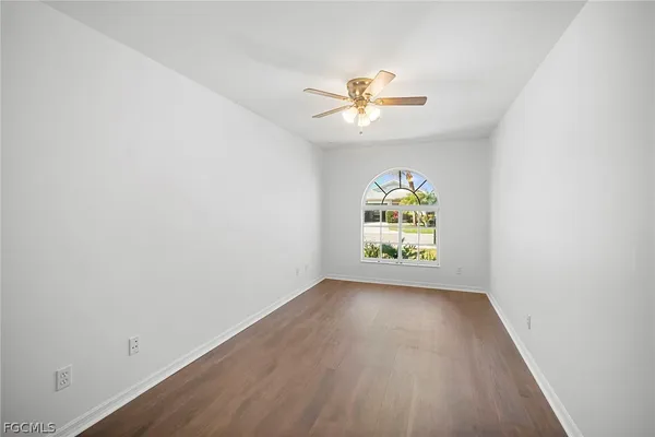 an empty room with windows and ceiling fan