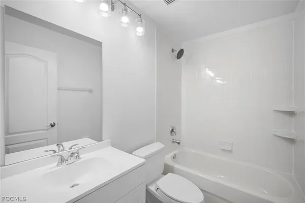 a bathroom with a bathtub shower sink vanity mirror and toilet