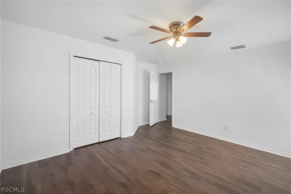 an empty room with wooden floor and ceiling fan