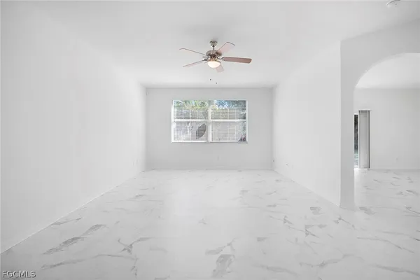 an empty room with a chandelier fan and windows