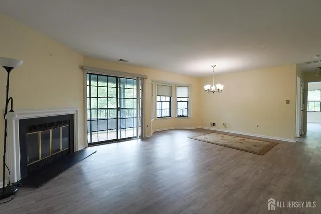 an empty room with wooden floor fireplace and windows