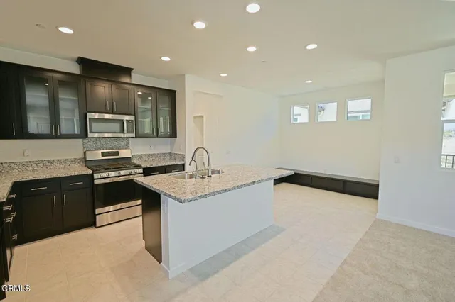 a kitchen with stainless steel appliances granite countertop a sink and a stove top oven with wooden floor