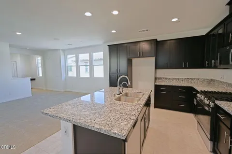 a kitchen with kitchen island granite countertop a stove and a sink