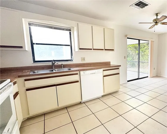 a kitchen with white cabinets appliances a sink and a window