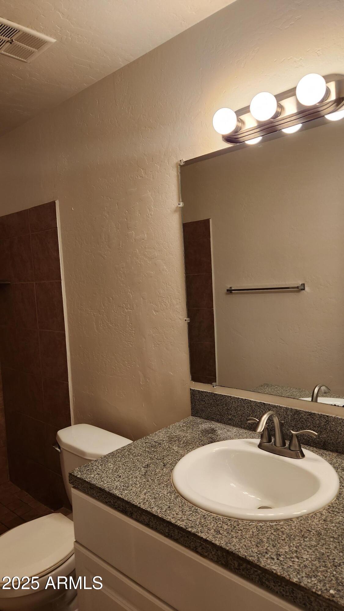3119 North 38th Street, Unit 10 Phoenix, AZ 85018 - Photo 8 of 20 a bathroom with a granite countertop sink a toilet and a mirror