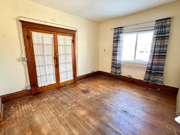 an empty room with wooden floor and windows
