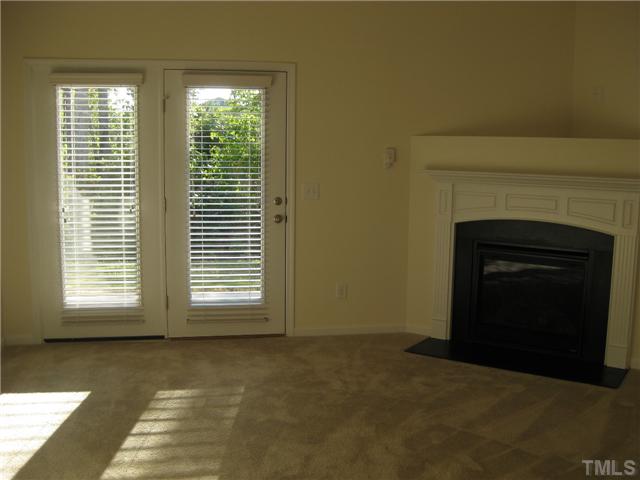 1648 Holly Grove Way Durham, NC 27713 - Photo 2 of 7 Late afternoon sun streams through the blinds on the french door into a living room featuring a gas log fireplace & plant shelf