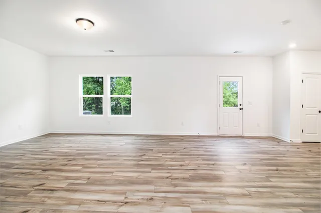 a view of an empty room with window and wooden floor