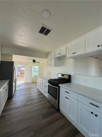 a large kitchen with stainless steel appliances granite countertop a stove and a wooden floors