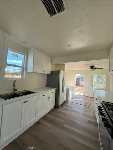 a kitchen with granite countertop a stove a sink and white cabinets with wooden floor