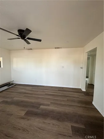 a view of a room with wooden floor and a ceiling fan