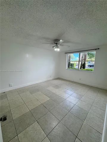 an empty room with windows and chandelier fan