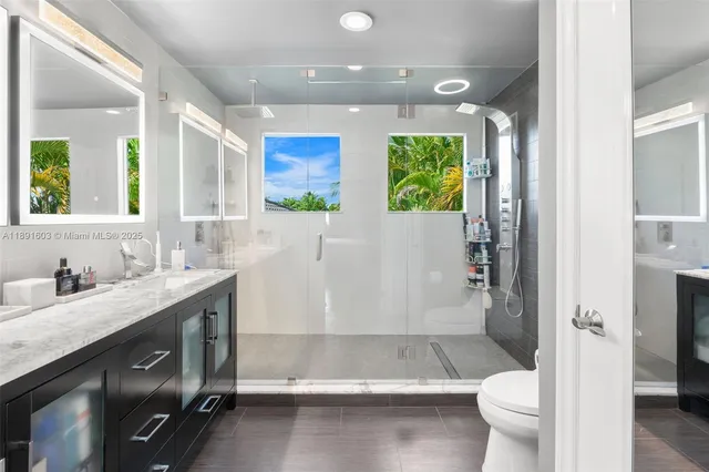 a bathroom with a granite countertop sink mirror vanity and toilet